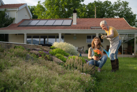 A woman and her granddaughter work in a garden after obtaining solar power. Solar cost using incentives helped prevent issues.