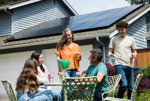 A family enjoys dinner in their back yard after hiring a solar company to install solar panels on their home